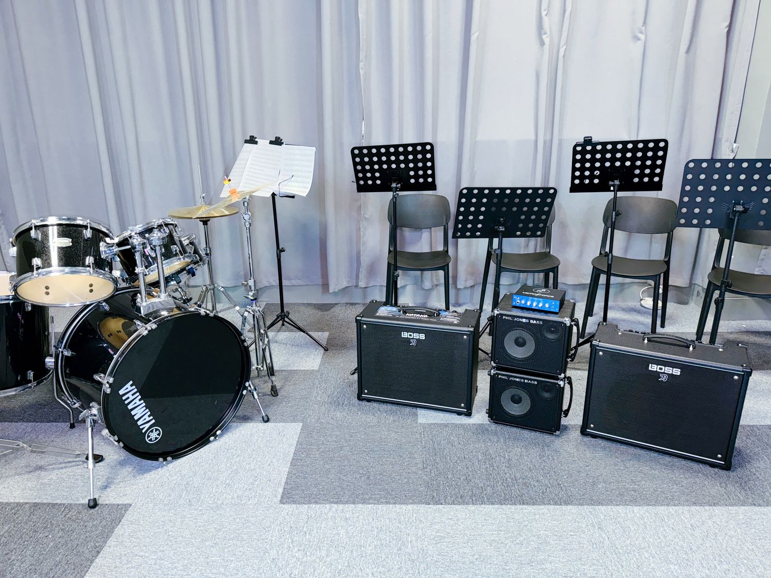A band rehearsal room with drum kit and backline